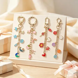 Détail de porte-clés DIY dorés avec des breloques colorées en alphabet et en cœur