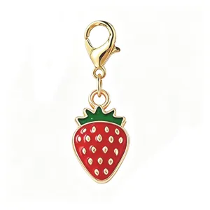 Detailed macro view of a red enamel strawberry charm pendant with gold lobster clasp