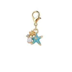 Detail van een blauwe zeester bedel met gouden karabijnsluiting, parel en kristal