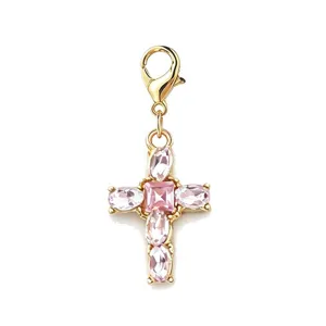 Close-up view of pink crystal cross charm with gold lobster clasp for DIY jewelry