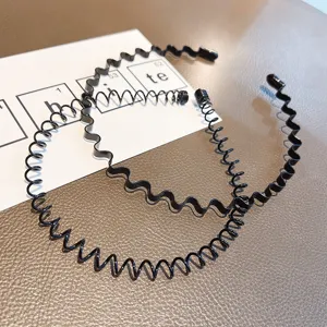 Primer plano de diademas negras de metal en espiral y onduladas para deporte y lavado facial
