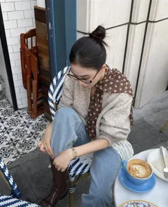 Detalle de un pañuelo de seda marrón con lunares lucido por una modelo en un café