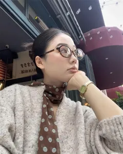 Foto de una mujer elegante con un pañuelo de seda marrón con lunares en el cuello