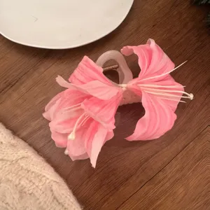 Vista detallada de una elegante pinza para el pelo con flores rosas y pétalos de lirio