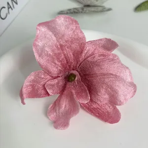 Detailed macro view of a 3D pink velvet orchid flower hair clip on a white plate
