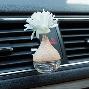 Close-up of car air vent perfume diffuser bottle with wooden cap and white flower reed.