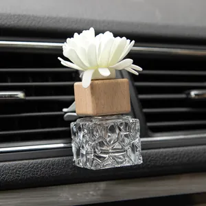 Car air vent perfume diffuser bottle featuring a wooden cap and white flower design.