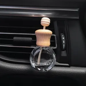 Transparent glass car perfume bottle with wooden cap clipped on vehicle air conditioning vent.