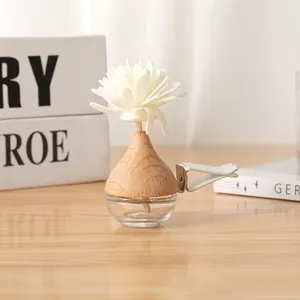 Car air vent perfume diffuser detail view, wooden cap and glass bottle with white flower.