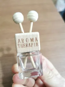 Square glass car aromatherapy bottle with wooden cap and diffuser sticks detail view