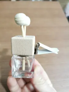 Square glass car diffuser empty bottle with wooden cap and air vent clip accessory.