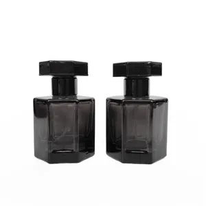 Détail de flacon de parfum en verre hexagonal noir, montrant la structure de pompe.