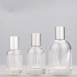 Close up detail of three clear glass perfume spray bottles featuring silver caps in sizes.