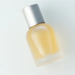 Close-up detail of frosted glass perfume spray bottle with silver cap holding cosmetic liquid.