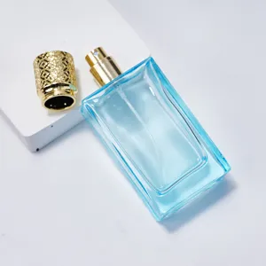 50ml blue glass perfume bottle with gold atomizer and carved cap, perfect cosmetic dispenser.