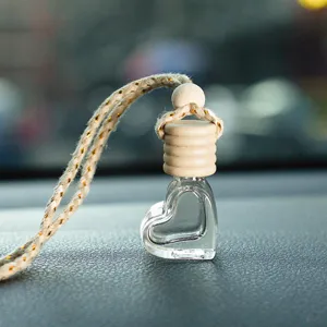Primo piano del flacone di profumo per auto in vetro a forma di cuore con tappo in legno.