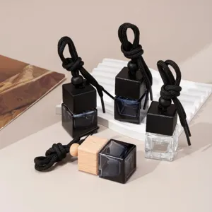 Detail shot of square glass car perfume diffuser bottle with wooden cap and black hanging rope.