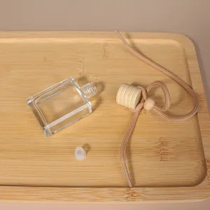 Primo piano della bottiglia di profumo per auto quadrata vuota, tappo in legno con corda.