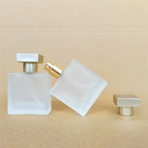 Square frosted glass perfume bottle detail view with gold spray pump and matching cap.