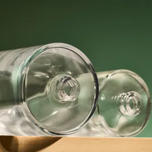 Clear glass perfume bottle detail shot showing screw neck and smooth bottom design.