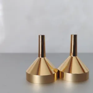 Nahaufnahme von zwei goldenen Metalltrichtern zum präzisen Abfüllen von Parfüm und Ölen.