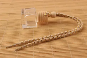 Detail shot of transparent square glass car perfume bottle with wooden cap and gold woven rope.