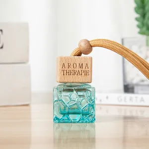Detailaufnahme der blauen geometrischen Glas-Autoparfümflasche mit Holzdeckel und Kordel.