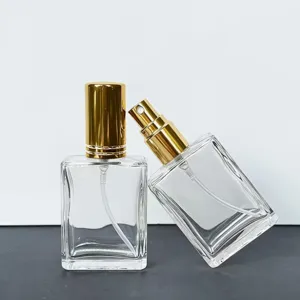 Clear glass perfume bottle detail showing square 15ml empty spray container with gold cap.