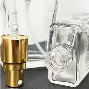 Detailed view of empty square glass perfume sub-bottle with gold fine mist spray nozzle.