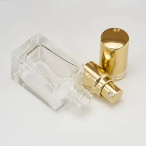 Close-up view of a clear square glass perfume bottle with a luxurious gold spray nozzle.