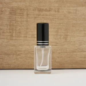 Detail shot of clear square 10ml glass perfume bottle with black cap and silver ring.