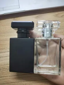 Detail view of square glass perfume bottles, featuring matte black and clear transparent designs.