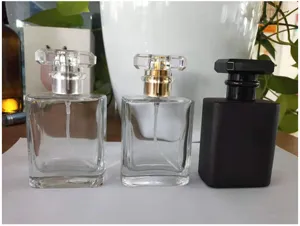 Detail view of square glass perfume bottles, clear and matte black empty cosmetic vials.