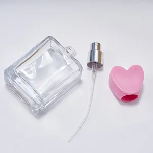 Leere quadratische Glasflasche mit rosa Herzdeckel und Sprühpumpe für Kosmetik und Parfum.