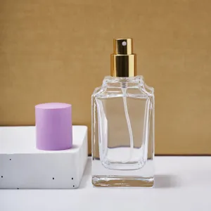 Detalle en primer plano del frasco de perfume de vidrio transparente vacío con bomba dorada.