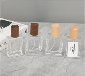 Clear square glass perfume bottles with wooden caps. Empty cosmetic spray bottles for fragrance.