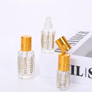 Clear glass essential oil roller bottle with gold cap and elegant floral print detail.