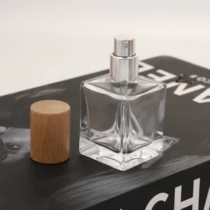 Clear square glass perfume bottle with wooden cap and silver spray nozzle for cosmetic sample.