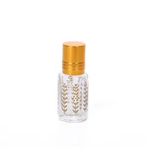 Detailed closeup of clear glass roller bottle with gold cap and floral design for perfume oils.