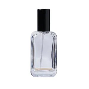 Clear glass perfume bottle close-up showing transparent body and fine spray nozzle detail.