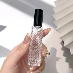 Close up of clear diamond pattern glass perfume spray bottle with black cap detail.