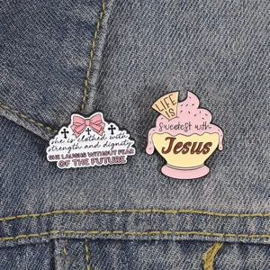 Primer plano de pines de esmalte religiosos con diseño de cupcake de Jesús y cintas