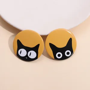 Detailed shot of two cute round tinplate badges featuring black cat cartoon designs