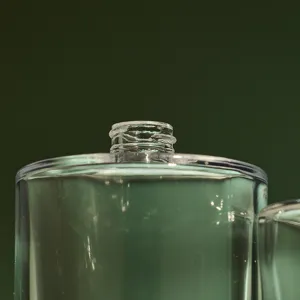 Close-up detail of a clear glass perfume bottle neck with threaded design for refillable use.