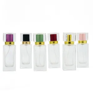 Clear glass perfume bottle detail shot showing square crystal cap and colored spray pump design.