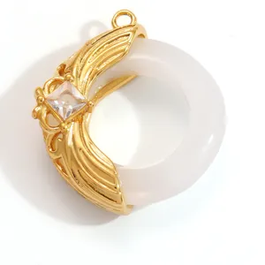 Close-up detail of a gold stainless steel pendant with a white ring and square crystal