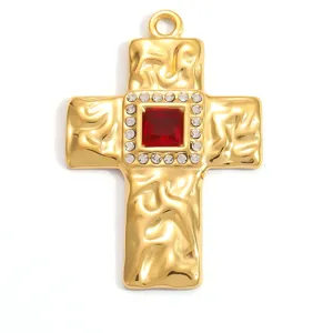Detail view of a hammered gold stainless steel cross pendant with central red gemstone.