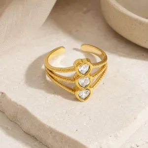 Dettaglio anello aperto in acciaio dorato con tre zirconi trasparenti a forma di cuore