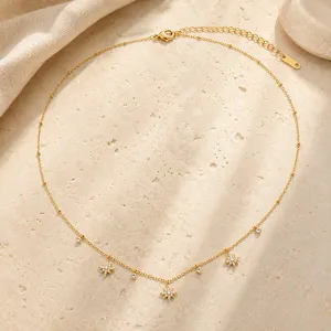 Primer plano de collar de acero inoxidable dorado con colgantes de estrella de circonia.