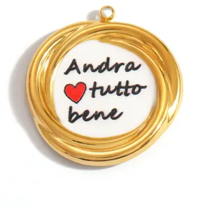 Macro view of a gold circular pendant featuring 'Andra tutto bene' text and heart
